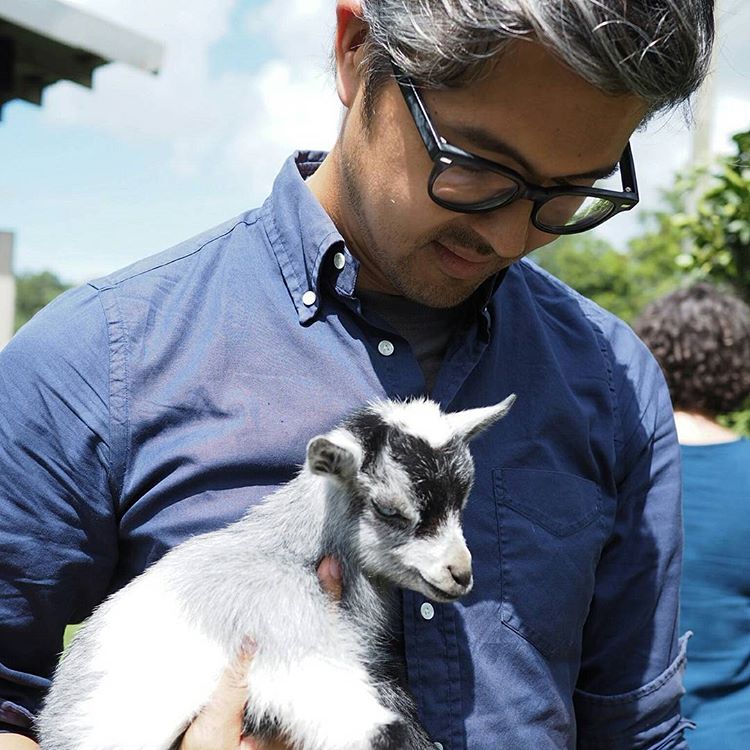 Jeff pictured holding a baby goat with grey hair