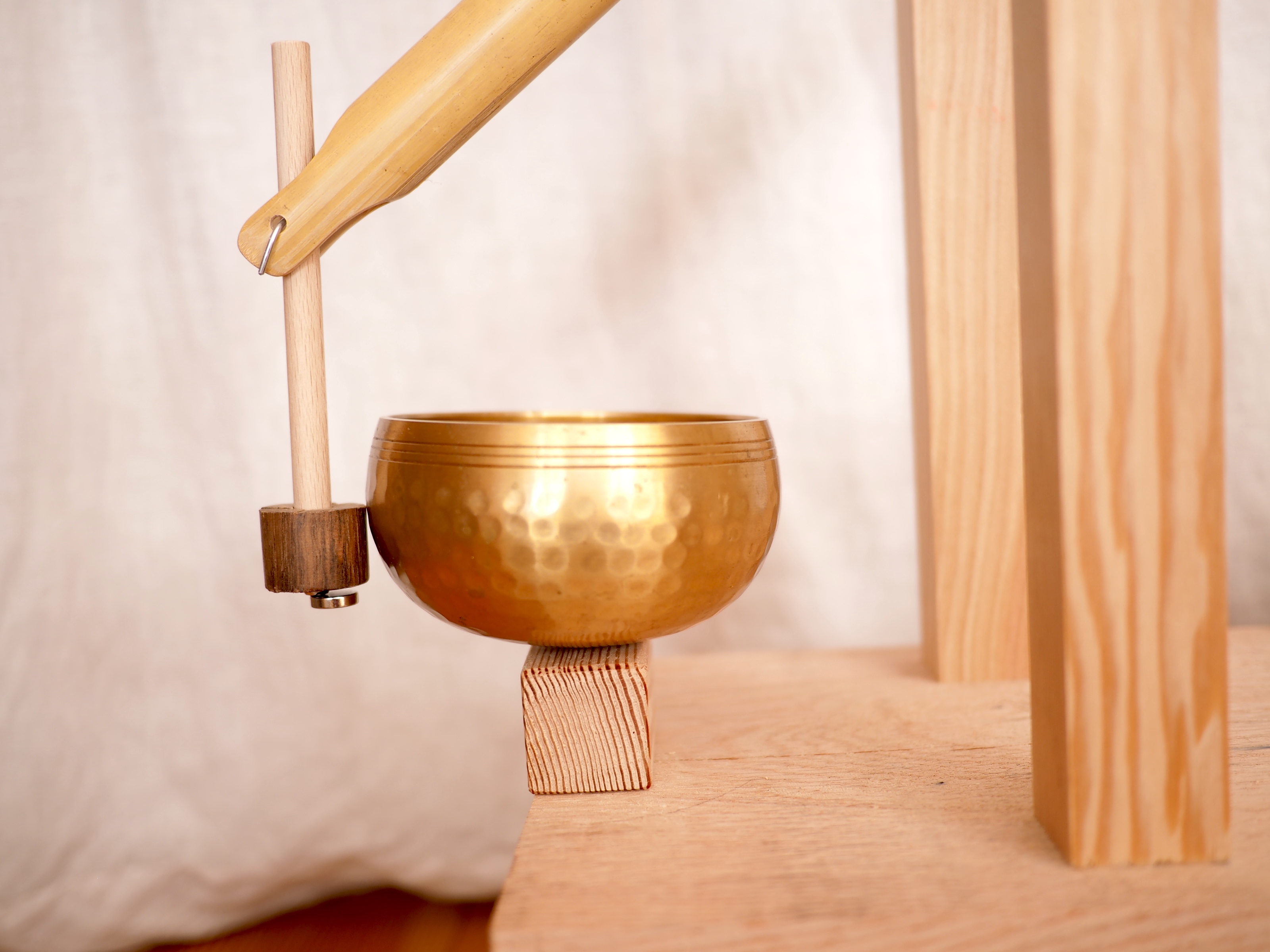 A closeup of the singing bowl and a hanging wooden mallet touching it.