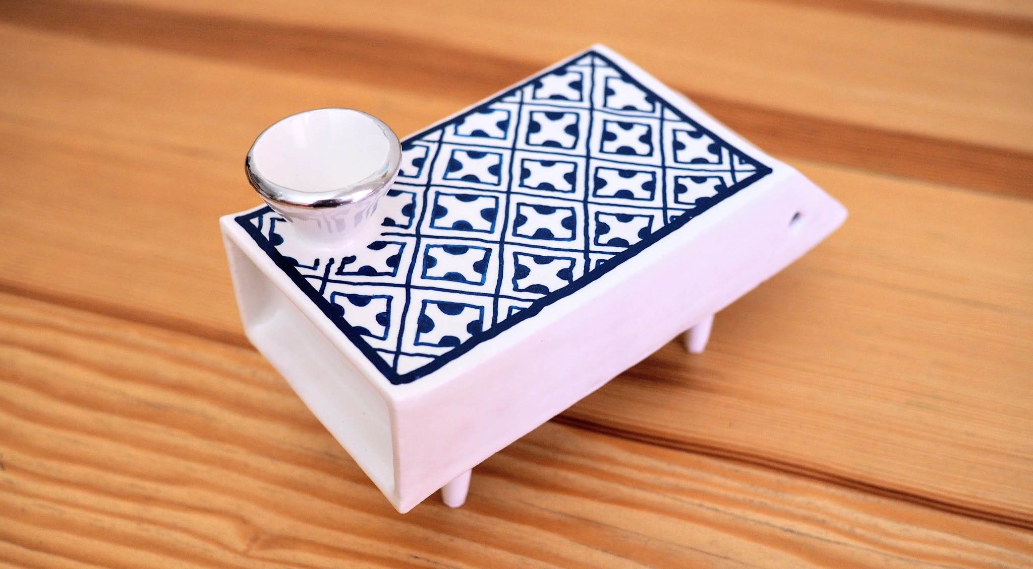 a poreclain box on four short legs, with blue checkered pattern and a porcelain cone on top
